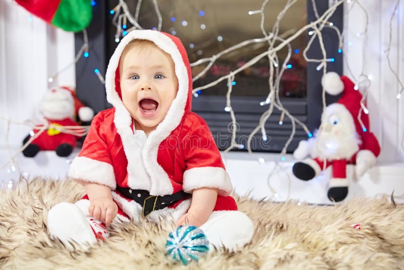 Peu de bébé de Noël dans le costume de Santa L'enfant tenant la boule bleue près des vacances allume le fond