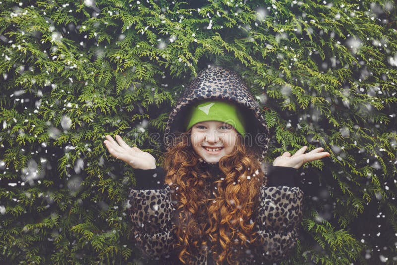 Peu de fille de cheveux bouclés près d'arbre vert d'hiver photo libre de droits Peu de fille de cheveux bouclés près d'arbre vert d'hiver photo libre de droits