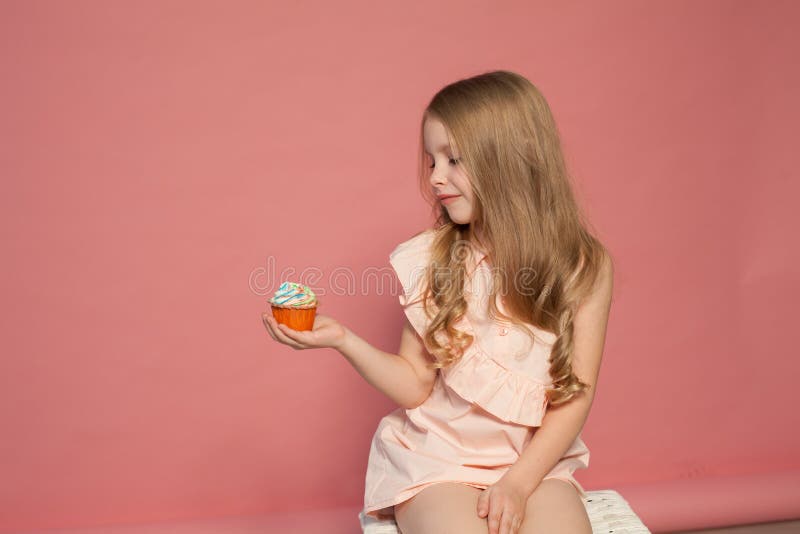 Peu de fille manger le gâteau doux avec le petit gâteau crème photo stock Peu de fille manger le gâteau doux avec le petit gâteau crème photo stock