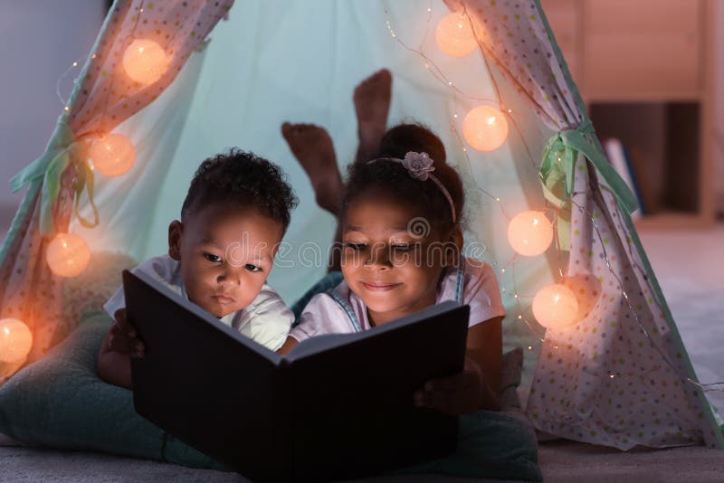 Peu enfants afro-américains lisant l'histoire pour endormir dans le taudis