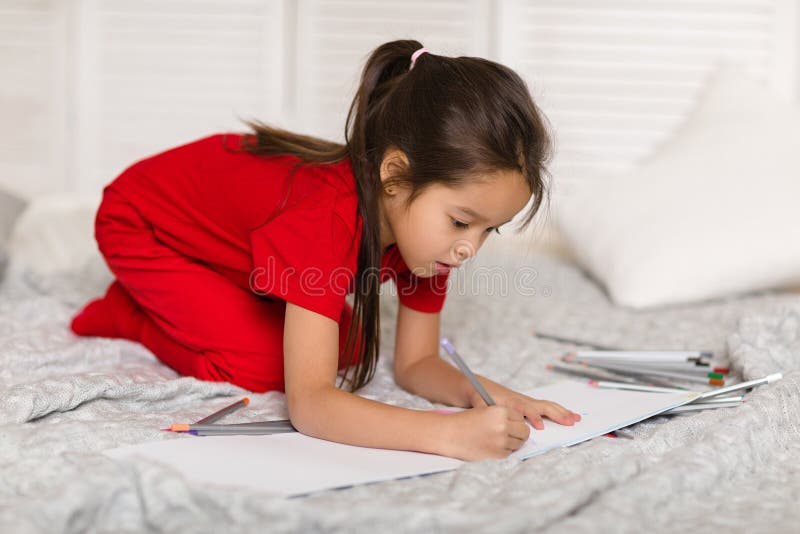 Peu fille d'enfant dessine avec des crayons ? la maison photographie stock libre de droits Peu fille d'enfant dessine avec des crayons ? la maison photographie stock libre de droits