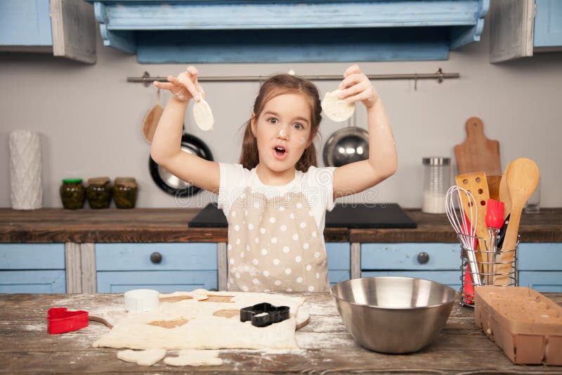 Peu fille dans la cuisine fabrique des biscuits à partir de la pâte avec différentes formes dans la cuisine Peu aide, faite ma photo stock Peu fille dans la cuisine fabrique des biscuits à partir de la pâte avec différentes formes dans la cuisine Peu aide, faite ma photo stock