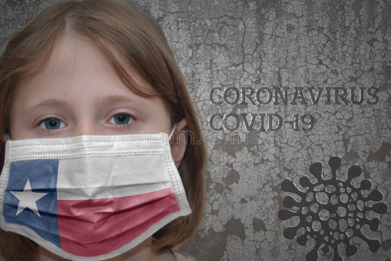 Little girl in medical mask with texas state flag stands near the old vintage wall with text coronavirus, covid, and virus picture. Stop virus. Little girl in medical mask with texas state flag stands near the old vintage wall with text coronavirus, covid, and virus picture. Stop virus