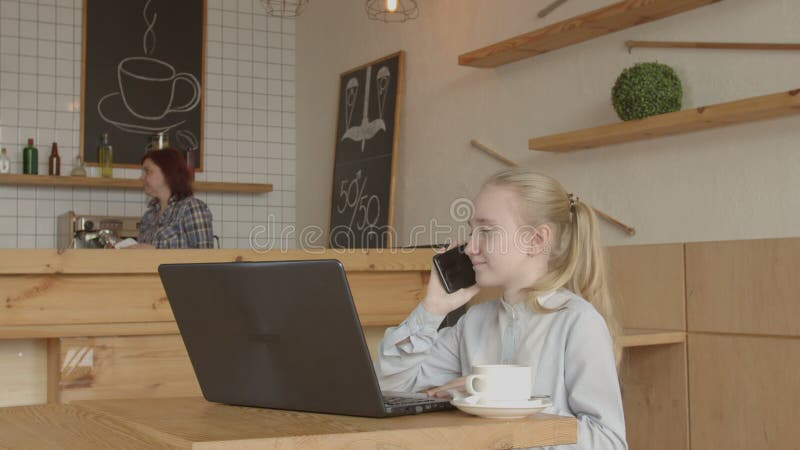 Peu fille s'asseyant à la table de café utilisant l'ordinateur portable banque de vidéos