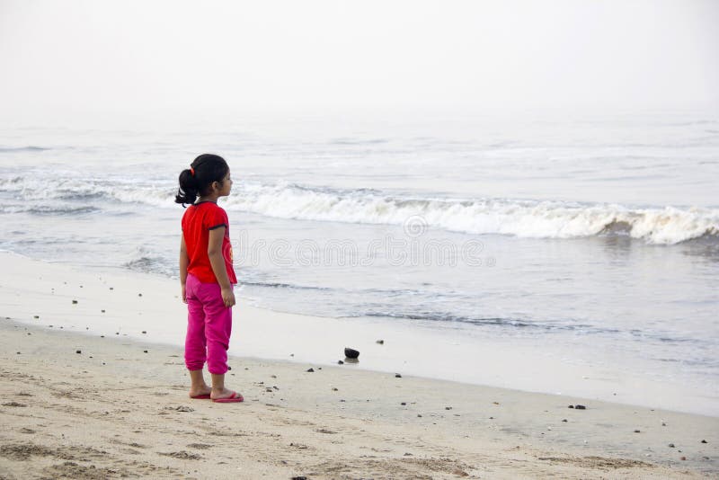 Peu fille, seul se tenant, regardant la mer, plage d'Alibag, Inde images stock Peu fille, seul se tenant, regardant la mer, plage d'Alibag, Inde images stock