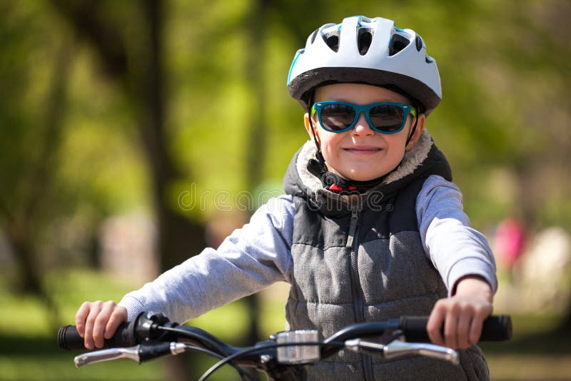 Peu gar?on apprend ? monter un v?lo en parc Le gar?on mignon dans des lunettes de soleil monte un v?lo Enfant de sourire heureux photos stock Peu gar?on apprend ? monter un v?lo en parc Le gar?on mignon dans des lunettes de soleil monte un v?lo Enfant de sourire heureux photos stock