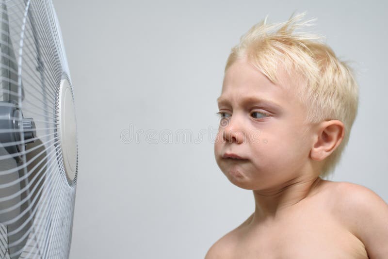 Peu garçon blond regarde une fan soupçonneusement Concept d'? t? photo libre de droits