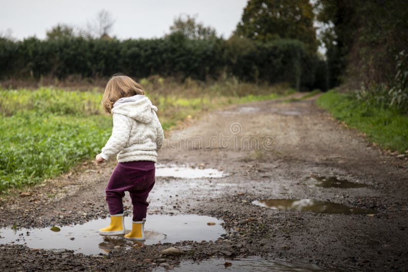 Peuter het bespatten in vulklei in modderige landweg stock afbeeldingen
