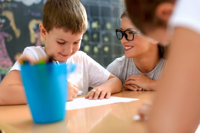 Peuterleraar die slimme glimlachende jongen bij kleuterschool bekijken stock afbeeldingen Peuterleraar die slimme glimlachende jongen bij kleuterschool bekijken stock afbeeldingen
