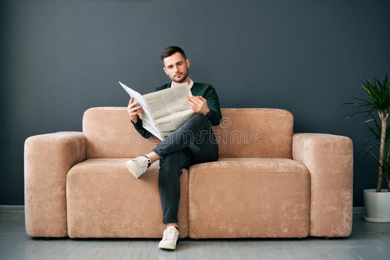Pewny siebie młody człowiek czyta gazetę i najnowsze wiadomości rano