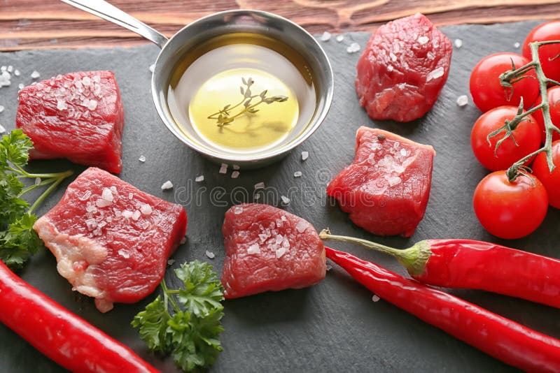 Pezzi di carne cruda, di olio d'oliva e di spezie sulla tavola immagini stock libere da diritti Pezzi di carne cruda, di olio d'oliva e di spezie sulla tavola immagini stock libere da diritti