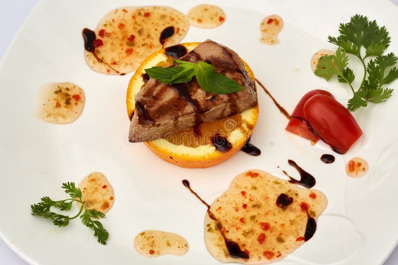 Pezzo di carne torrefatta sulla fetta arancione sulla piastra fotografie stock libere da diritti
