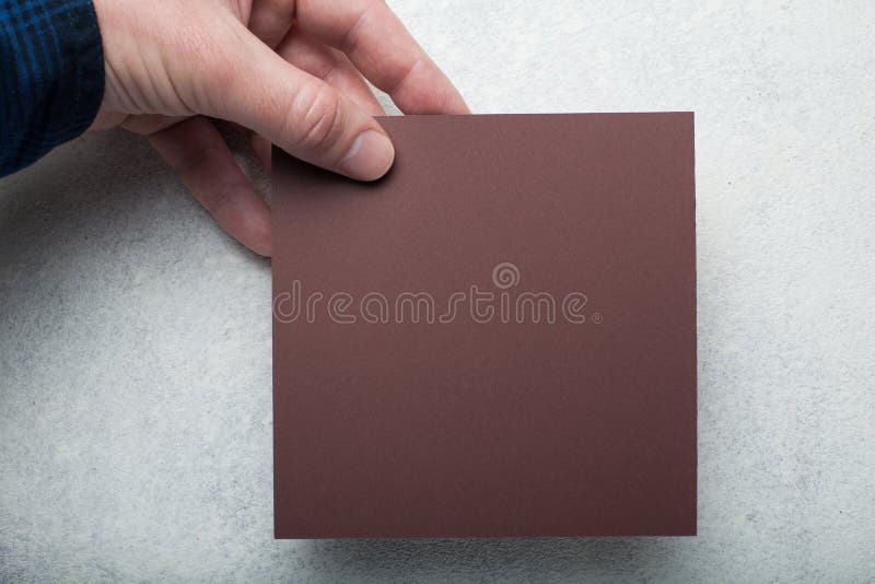 Pezzo di carta quadrato marrone in una mano europea su un fondo bianco d'annata fotografie stock Pezzo di carta quadrato marrone in una mano europea su un fondo bianco d'annata fotografie stock