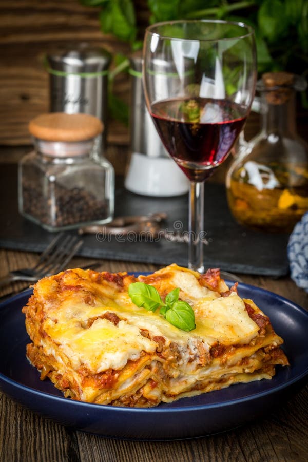 Pezzo di lasagne al forno calde saporite con vino rosso fotografia stock Pezzo di lasagne al forno calde saporite con vino rosso fotografia stock
