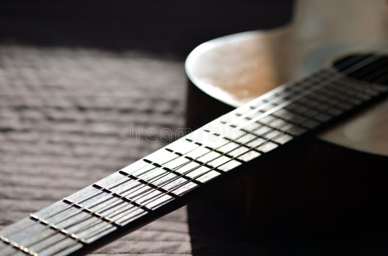 A peça da guitarra acústica velha iluminou-se pelo sol imagens de stock A peça da guitarra acústica velha iluminou-se pelo sol imagens de stock