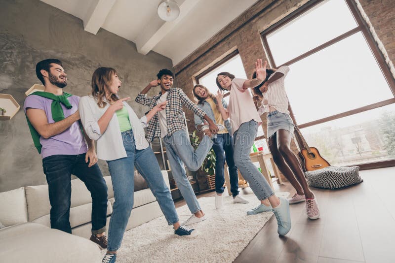 Full length body size view of lovely cool funky cheerful friends dancing having fun rest in house modern loft brick style interior indoors. Full length body size view of lovely cool funky cheerful friends dancing having fun rest in house modern loft brick style interior indoors.