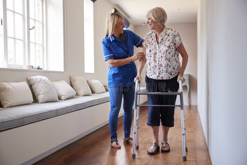 Pflegen Sie helfende ältere Frau, einen gehenden Rahmen zu benutzen stockbild Pflegen Sie helfende ältere Frau, einen gehenden Rahmen zu benutzen stockbild
