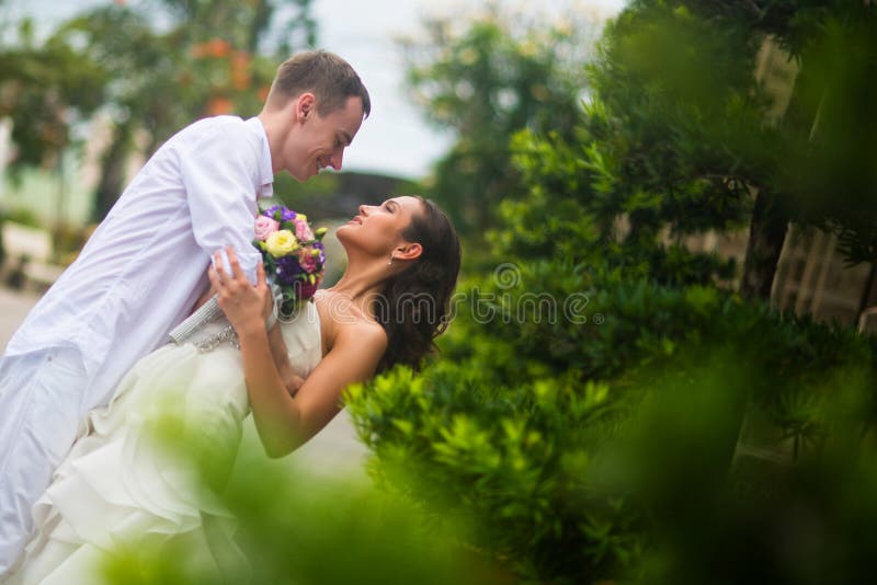 Pflegen Sie sich umarmte die Braut und lehnte sie, um zu küssen Hochzeitspaarumarmen lizenzfreies stockfoto Pflegen Sie sich umarmte die Braut und lehnte sie, um zu küssen Hochzeitspaarumarmen lizenzfreies stockfoto