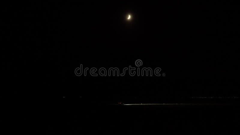 Phares de voiture conduisant route sombre sous la lune brumeuse du croissant