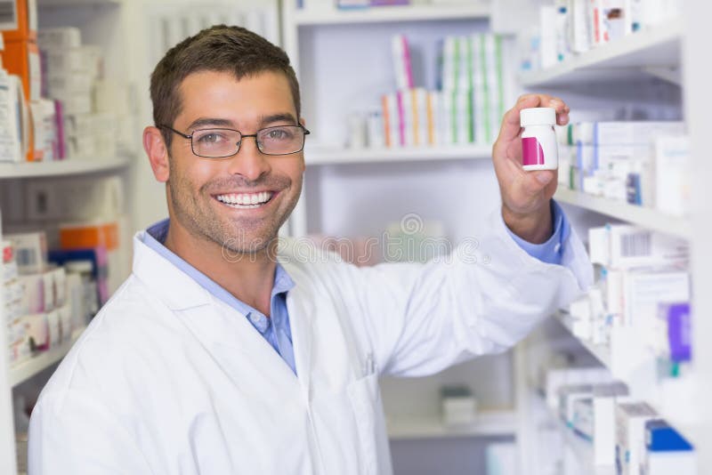 Pharmacien beau tenant le pot de médecine image stock Pharmacien beau tenant le pot de médecine image stock