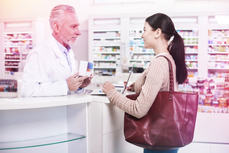 Pharmacien montrant la boîte de médecine à un client images stock Pharmacien montrant la boîte de médecine à un client images stock