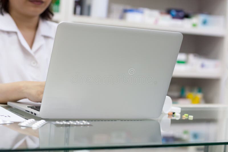 Pharmacist with Laptop Computer and Medication in the Pharmacy Stock
