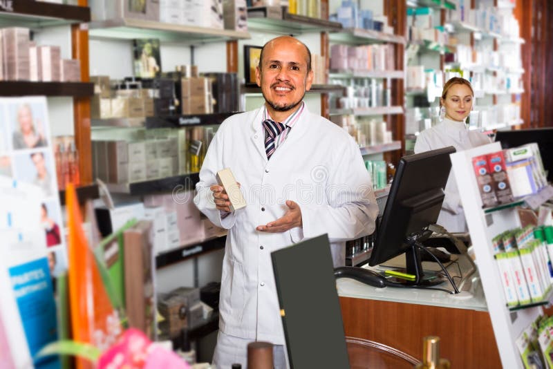 Two cheerful pharmacists standing with a cash desk in the pharmacy