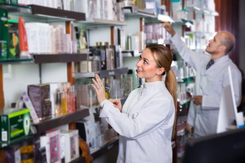 Two professional pharmacists standing with a cash desk in the pharmacy