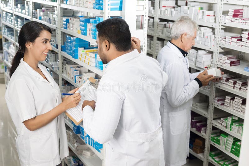 Pharmacists Working By Shelves In Pharmacy royalty free stock photography Pharmacists Working By Shelves In Pharmacy royalty free stock photography