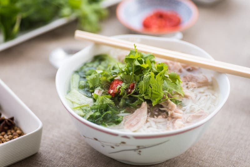 Pho ga soup with the serving sauces, herbs and spices