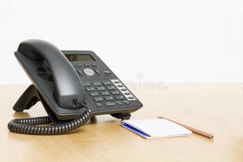 Phone on desk with notepad on wooden desk