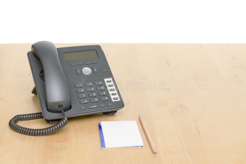 Phone on desk with notepad on wooden desk