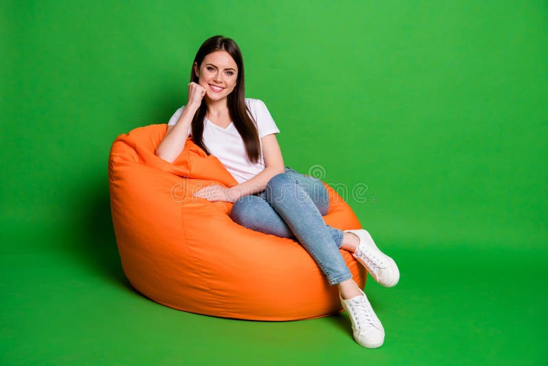 Photo of adorable cute brunette hair young woman fist cheek dress wear white t-shirt jeans footwear sit on pouf isolated