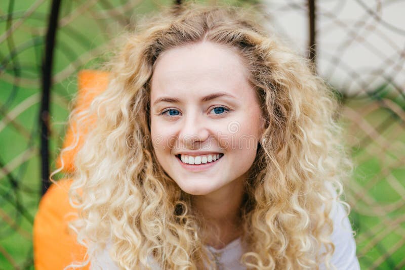 Photo Of Attractive Curly Blonde Female With Shining Smile Shows White