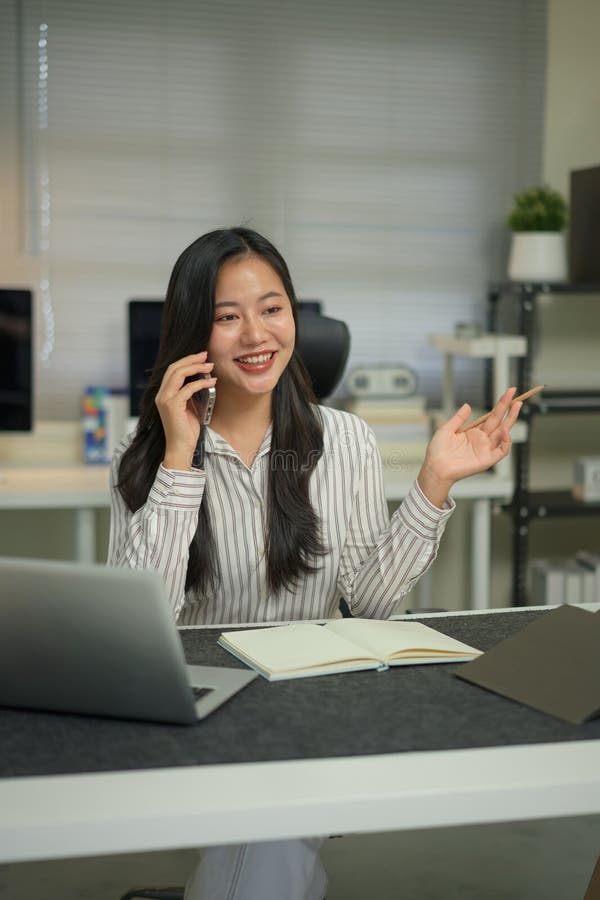 Photo a beautiful woman using a smartphone to calling someone while sitting in front a computer stock photos