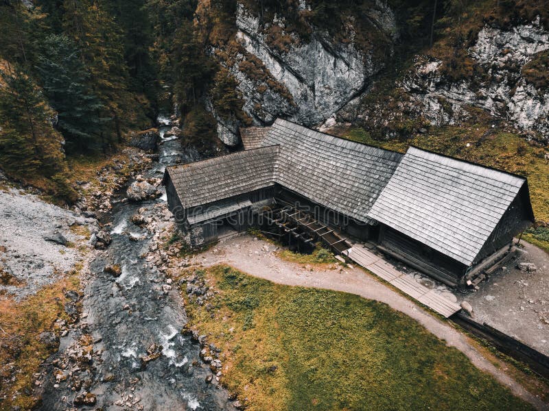 Photo of a beautiful wooden cabin with river in the forest from above - Mlyny Oblazy Slovakia - taken by drone. Old wooden mill