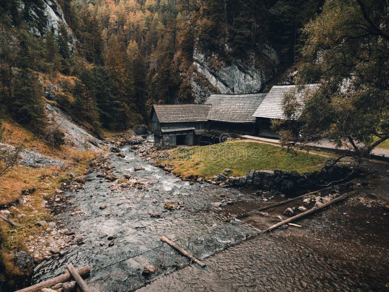 Photo of a beautiful wooden cabin with river in the forest from above - Mlyny Oblazy Slovakia - taken by drone. Old wooden mill