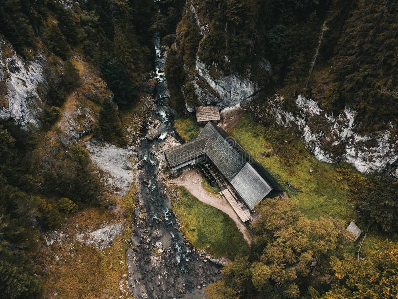 Photo of a beautiful wooden cabin with river in the forest from above - Mlyny Oblazy Slovakia - taken by drone. Old wooden mill