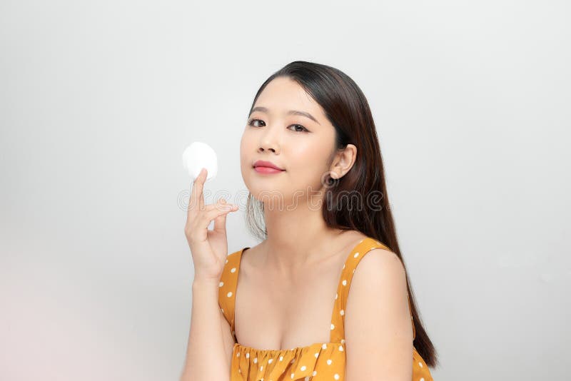 Photo of a beautiful young pretty asian woman with healthy skin posing naked  over white wall background holding cotton