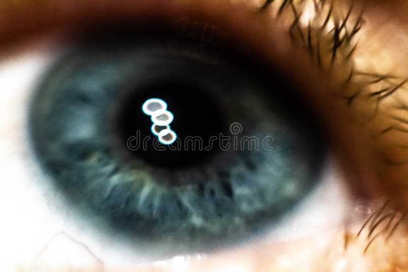 Photo of Blue Eye with 4 Points of Light Reflected in the Iris. Stock
