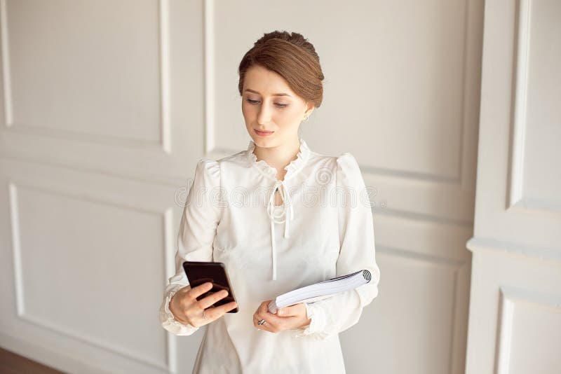 Photo business woman wearing suit, looking smartphone and holding documents in hands royalty free stock image Photo business woman wearing suit, looking smartphone and holding documents in hands royalty free stock image
