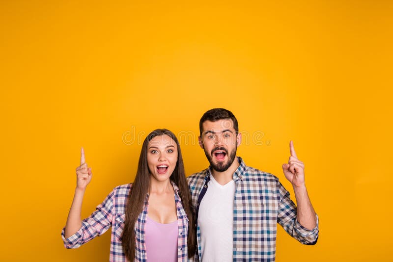 Photo charming lady handsome guy couple hugging showing novelty product directing fingers up empty space open mouth cool royalty free stock photography