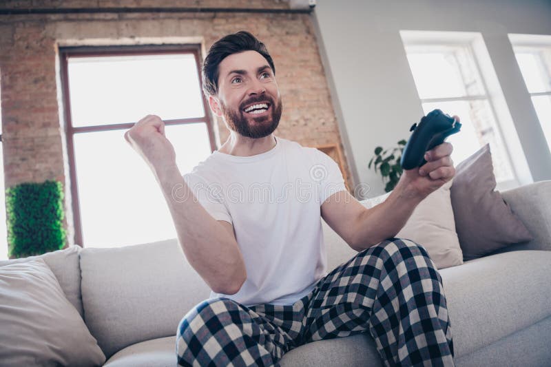 Photo of cheerful funny crazy man wear pajamas win level video game weekend indoors apartment flat stock images