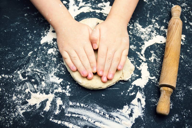 A photo of child hands with cutter making homemade traditional heart shape christmas cookies. An overhead photo of kid`s hands, s