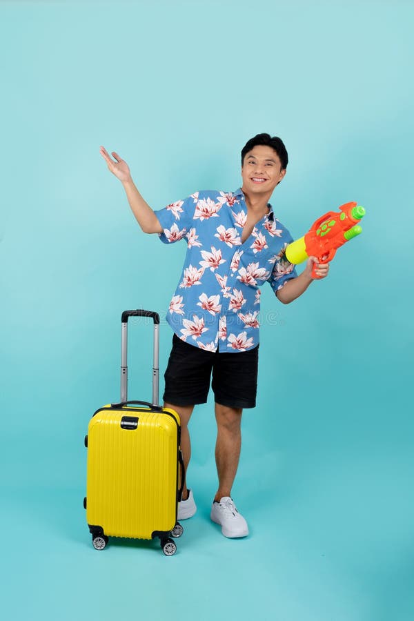 Photo complète du beau touriste asiatique en vêtements d'été avec pistolet à eau et bagages pendant le festival de songkran sur fo photos libres de droits