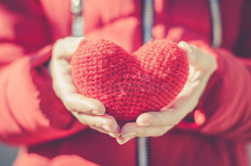 Girl holds a red heart. Valentine`s Day Gift. Photo conveys a festive mood. Beautiful bright day and a gift in the form of a heart in the hands of a young lady stock photography Girl holds a red heart. Valentine`s Day Gift. Photo conveys a festive mood. Beautiful bright day and a gift in the form of a heart in the hands of a young lady stock photography