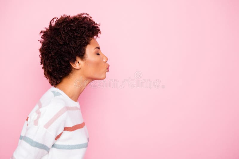 Photo of cute nice charming fascinating black woman kissing empty space standing side profile wearing white striped