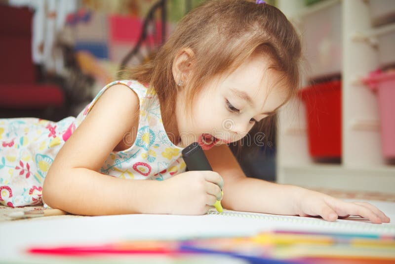 Photo d'aspiration de petite fille soigneusement dans le carnet avec le stylo de feutre photos libres de droits Photo d'aspiration de petite fille soigneusement dans le carnet avec le stylo de feutre photos libres de droits