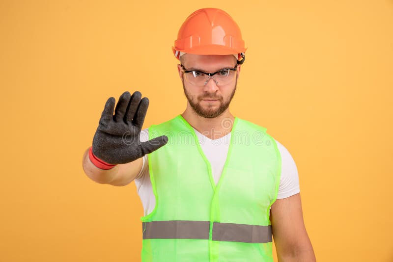 Photo d'un sérieux bâtisseur de cravate de sterne montrant un geste d'arrêt, portant un casque de construction de protection oran photo libre de droits Photo d'un sérieux bâtisseur de cravate de sterne montrant un geste d'arrêt, portant un casque de construction de protection oran photo libre de droits