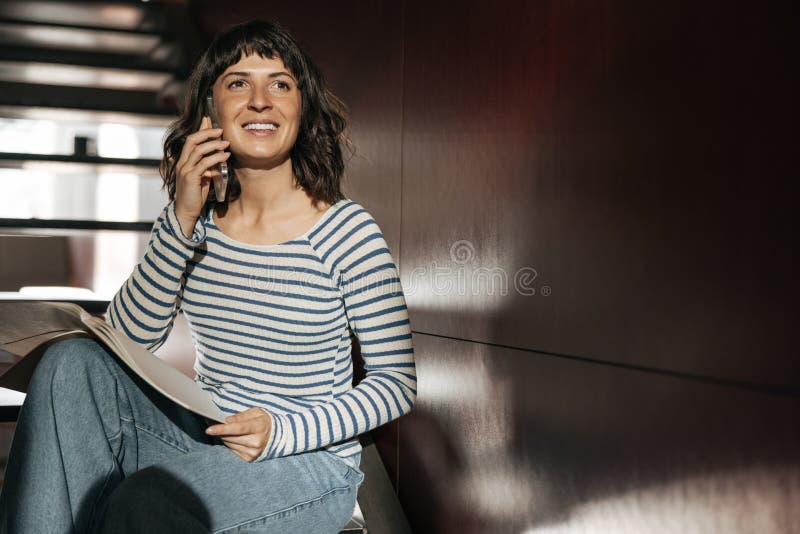 Photo d'une européenne souriante tenant un téléphone et écoutant regarder loin photographie stock